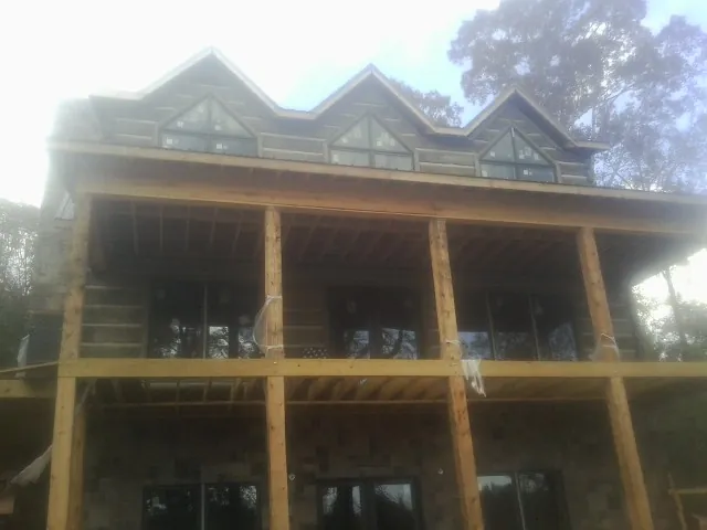 Dormers and porch framing on a large log home under construction — Roof Coating work by our crew in Leola