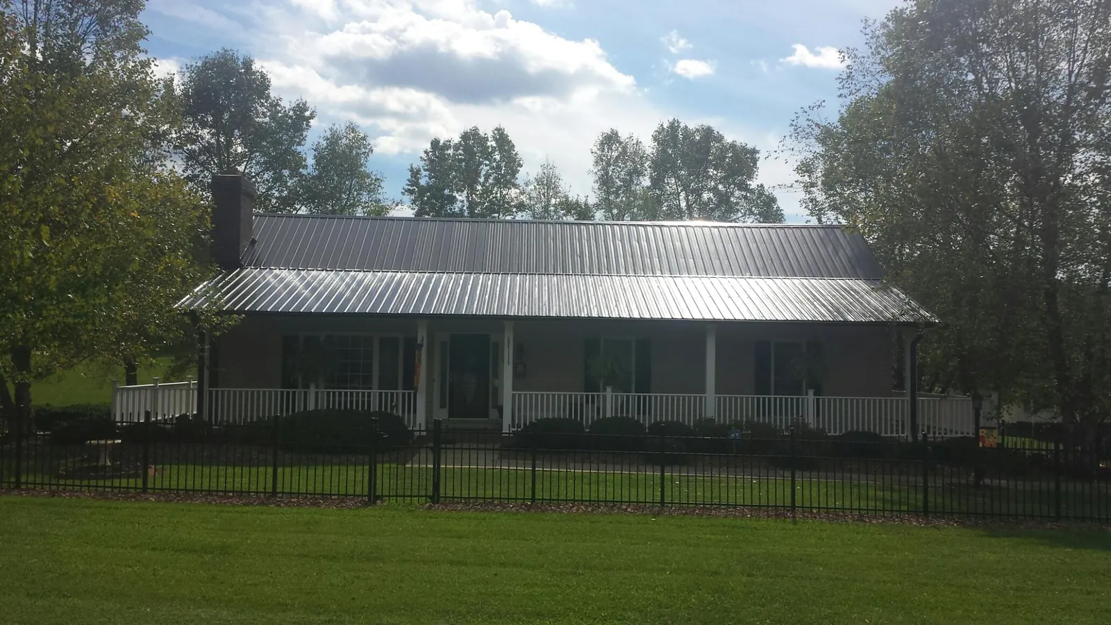 Gray metal roof on a brick ranch with a full width front porch — Gutter Guard Installation work by our crew in Leola
