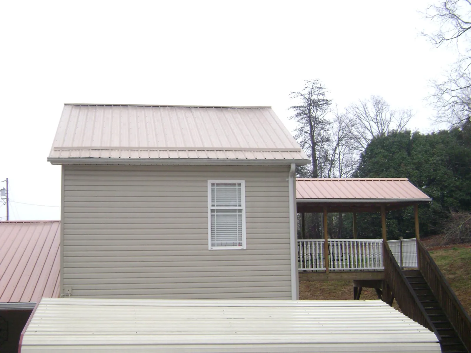 Tan metal roofs on a two story addition and attached porch, from a Roof Replacement job in Leola